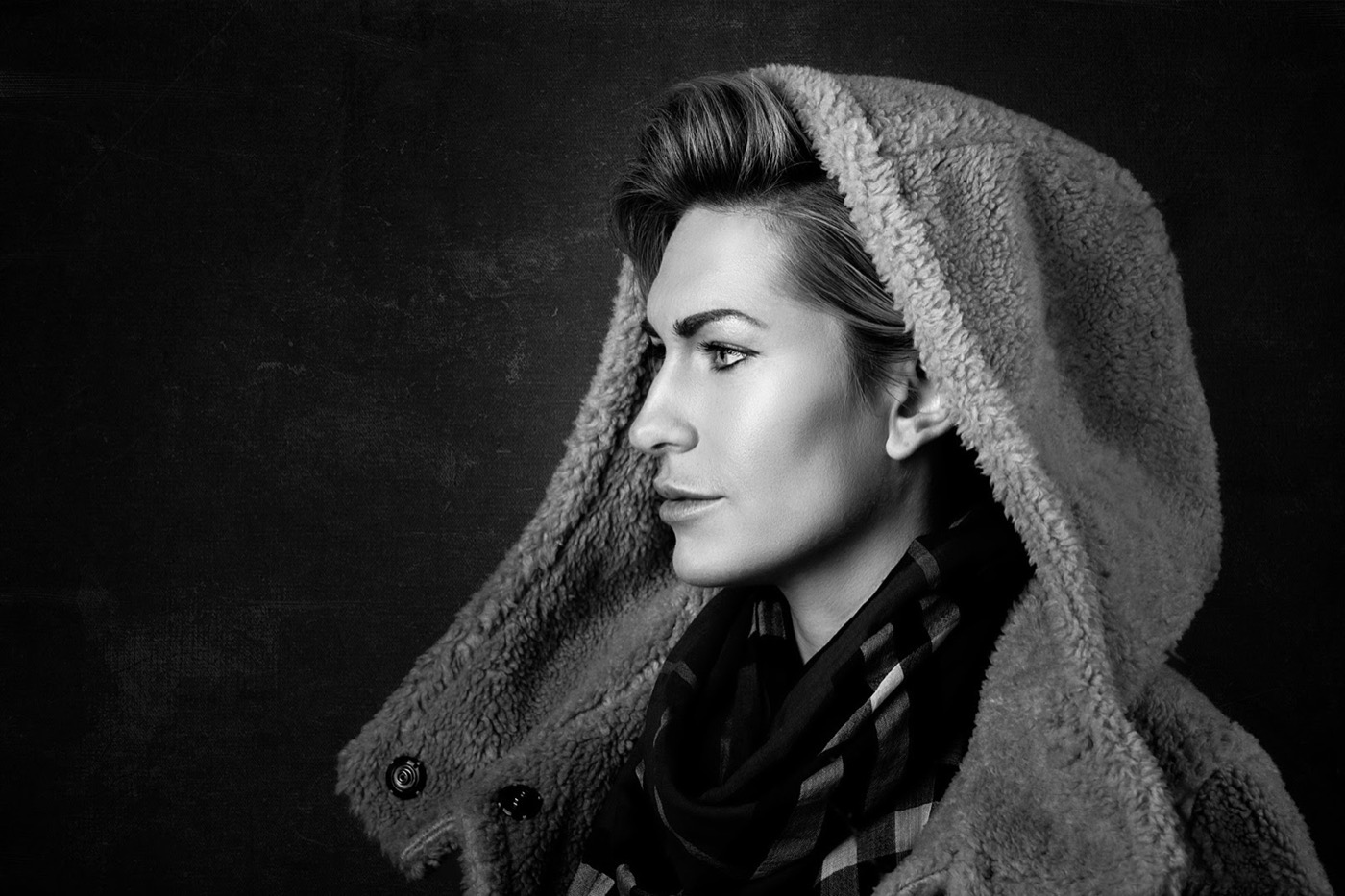 Black and white profile portrait of a woman in a hooded sheepskin coat